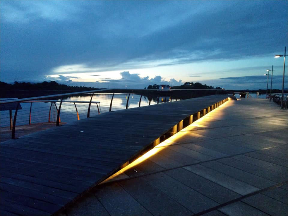 A wooden walkway on a pier, lit from underneath.