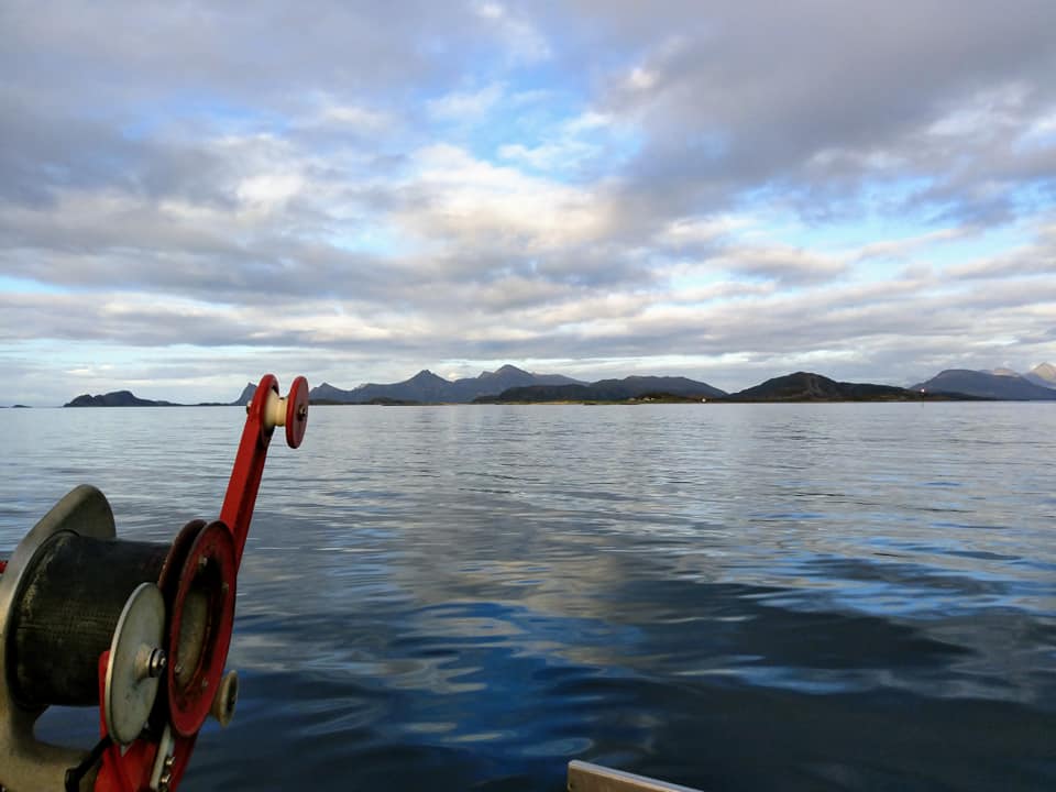 Calm waters with clouds and mountains in the distance.