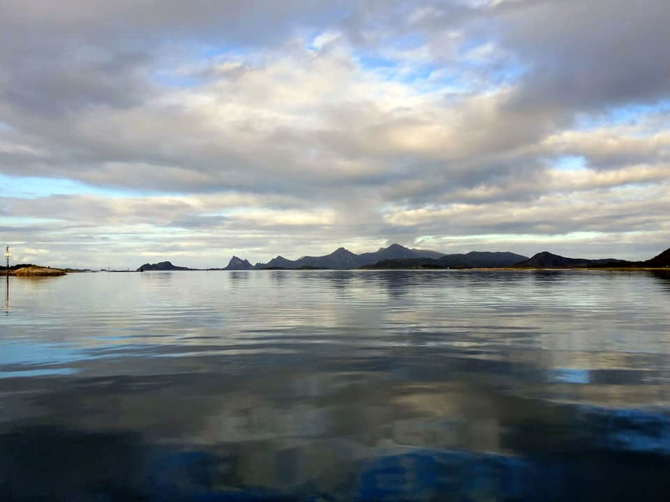 Extremely still waters with a row of mountains in the distance.