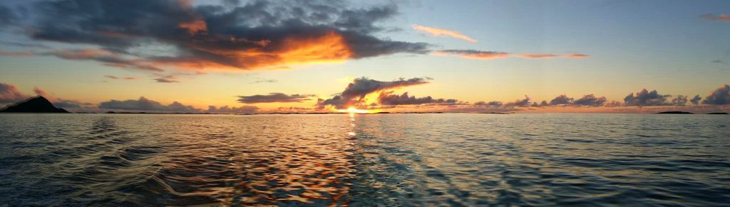 A wide lens shot of beautiful red and yellow sunset going into the water.