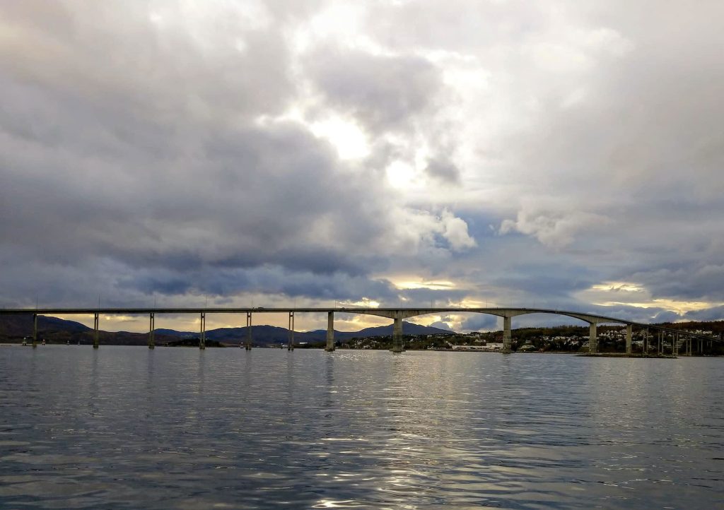 A wide shot of a long bridge going over a fjord.