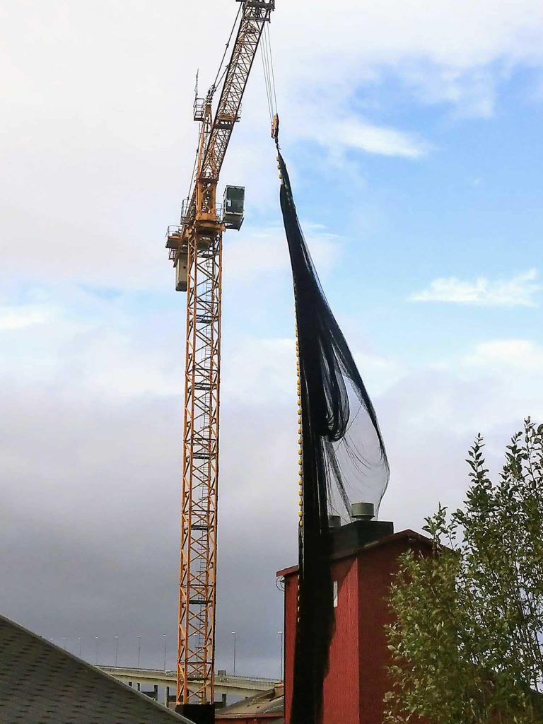 A crane lifting a massive fishing net off the ground.