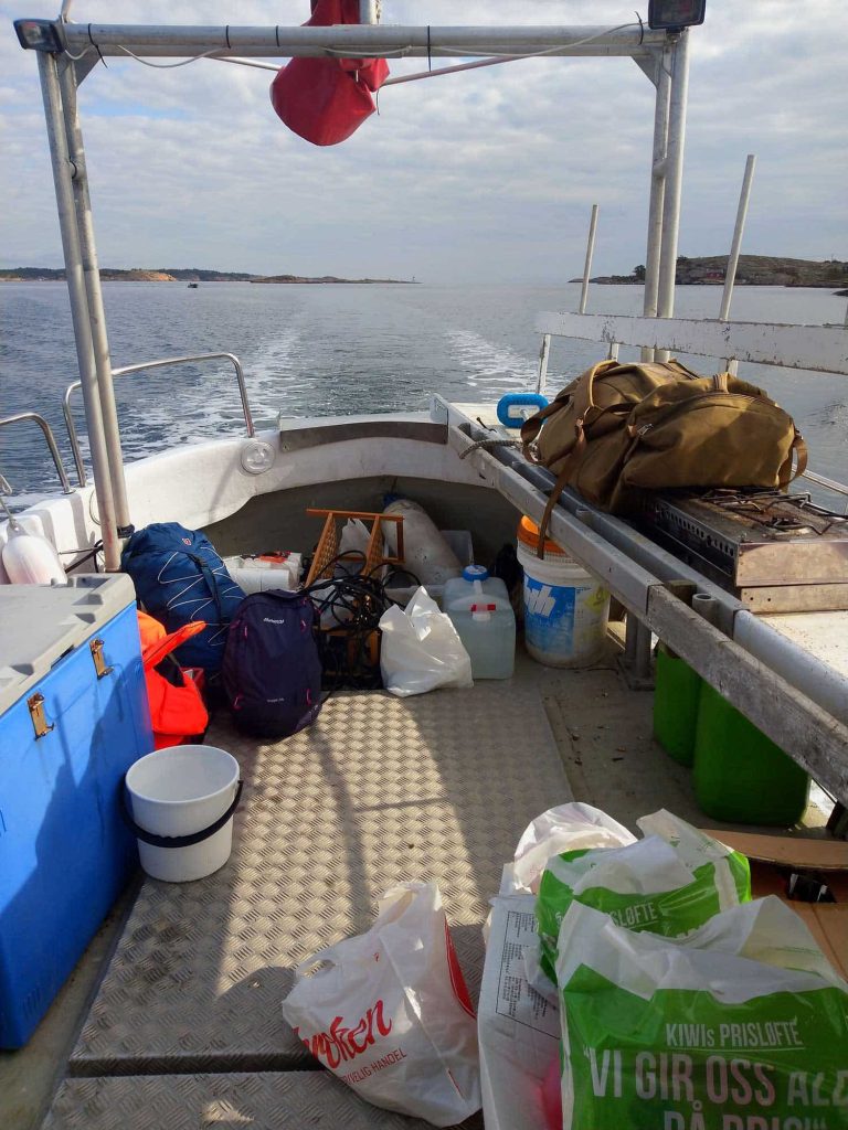 The deck of a small boat, filled with bags, boxes and garbage.