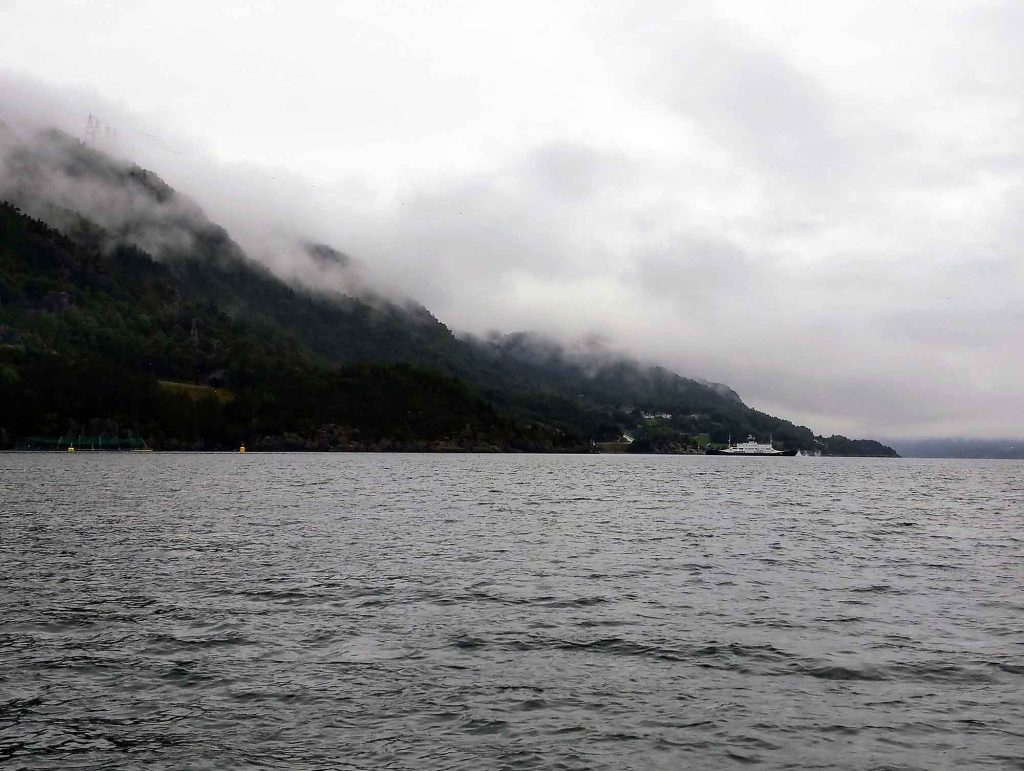 A misted mountain by the water.