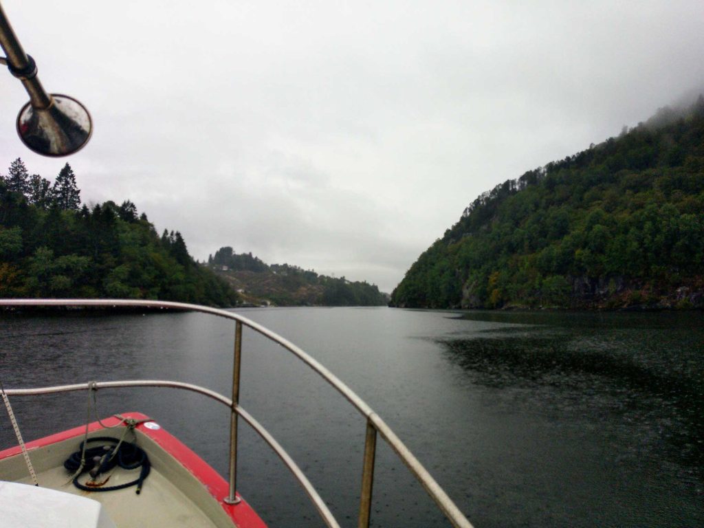 A view from the front of the boat, looking out over the water. A mountain and a hill is in the distance.