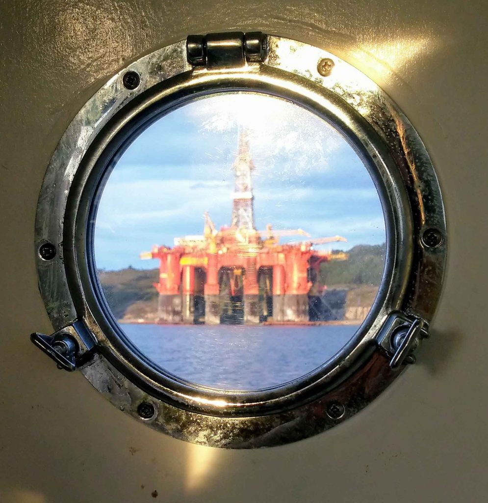 A round boat window looking out to a small oil platform.