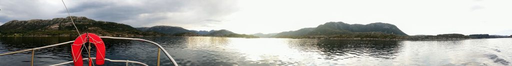 A wide lens view of a fjord with mountains in the background.