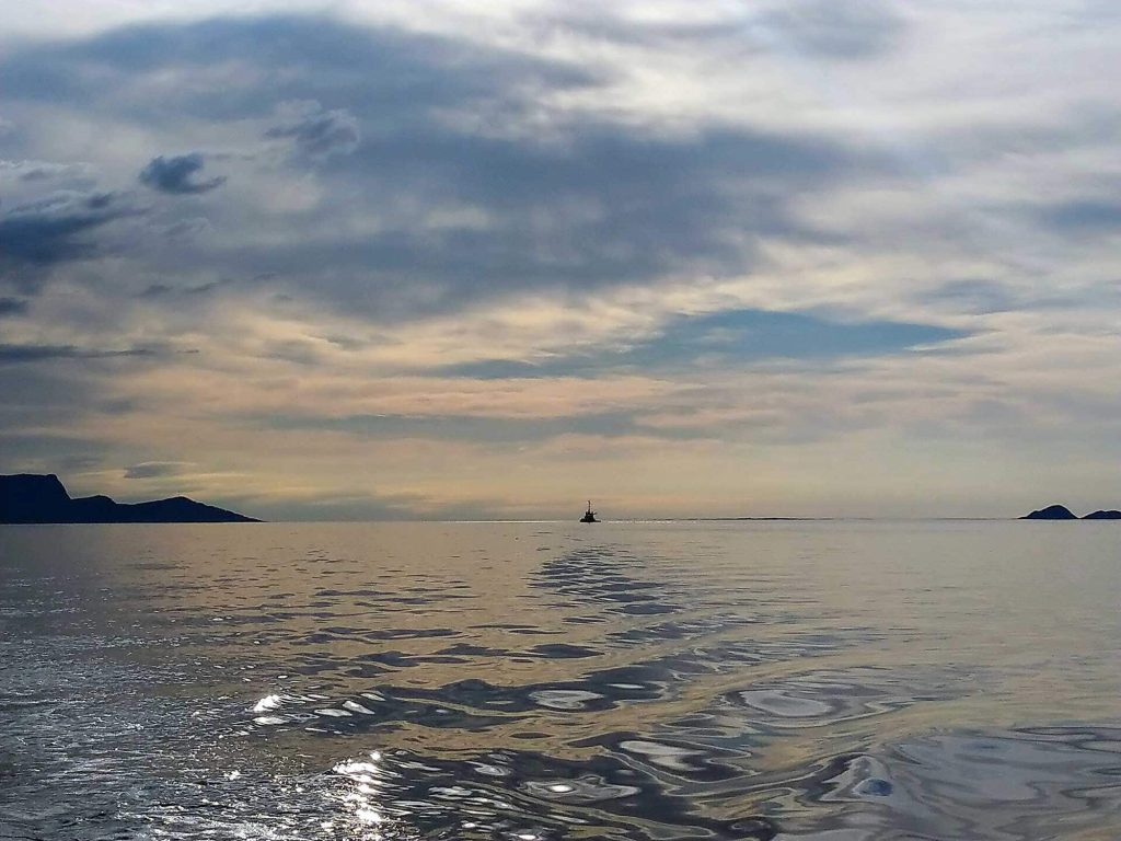 A broad view of the ocean and sky with a boat far away in the distance.