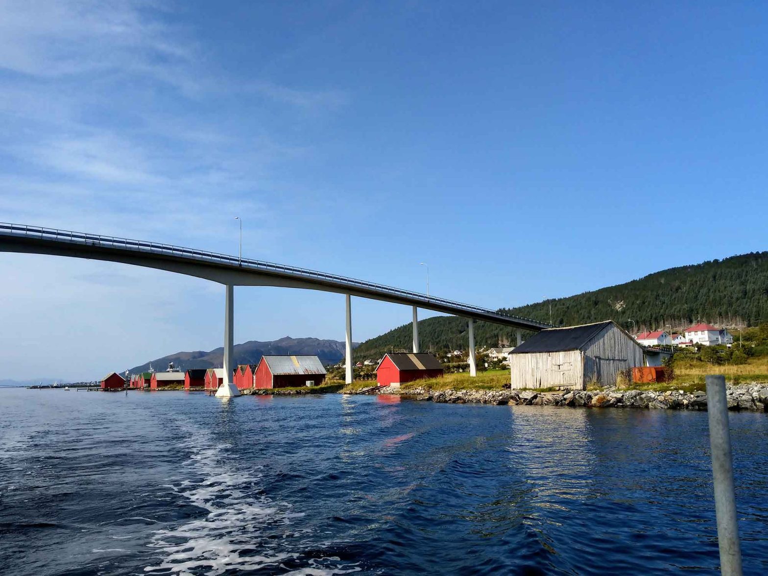 A bridge over water with a few houses along the shore.