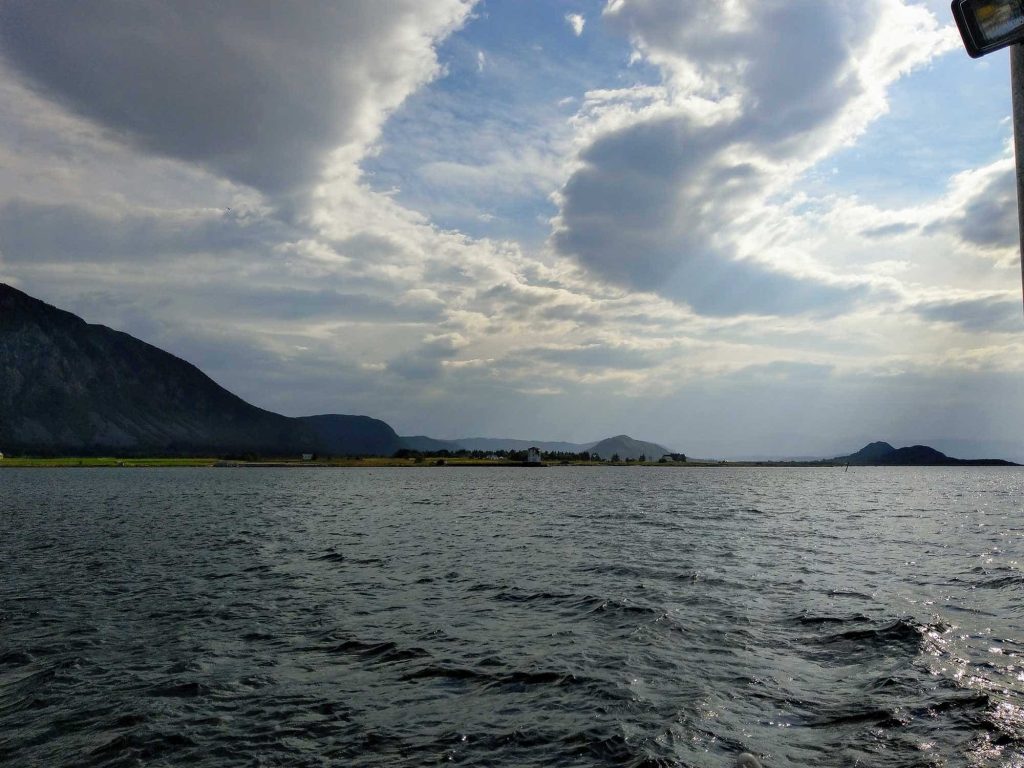 The ocean with some mountains in the distance and cloudy skies.