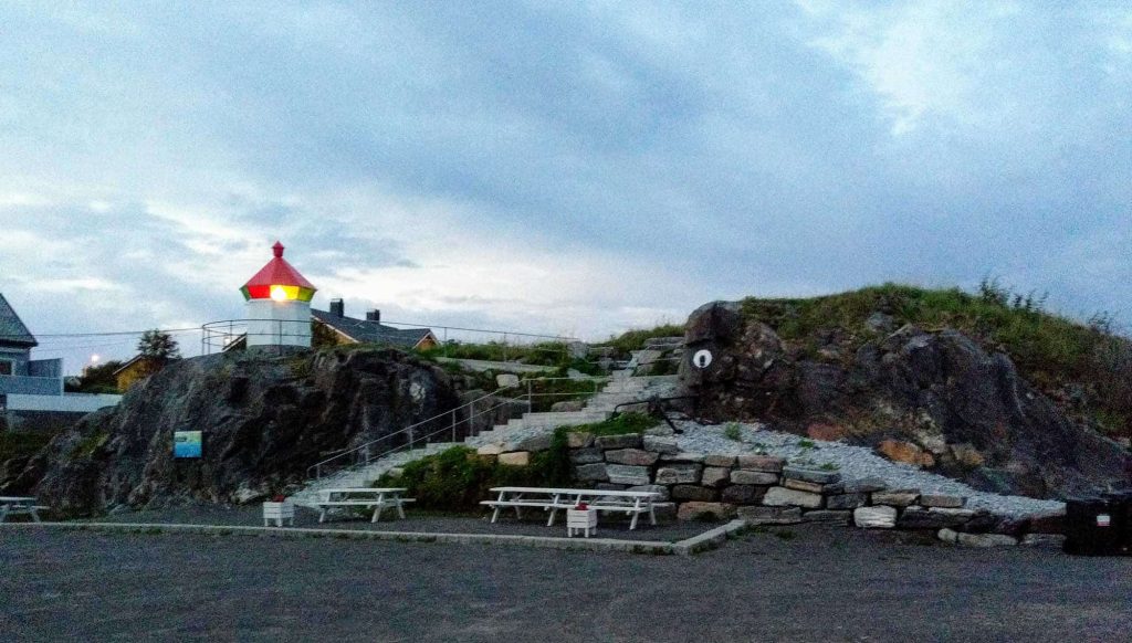 A little lighthouse by a small rock with some stairs leading up to it.