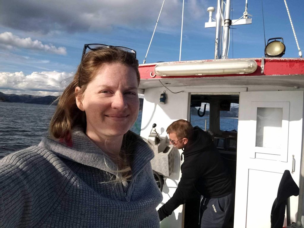 Selfie of me on the deck of Smolten, V leaning out of the wheelhouse in the background.