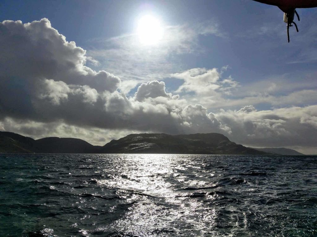 The sea, big clouds over a mountain in the distance.